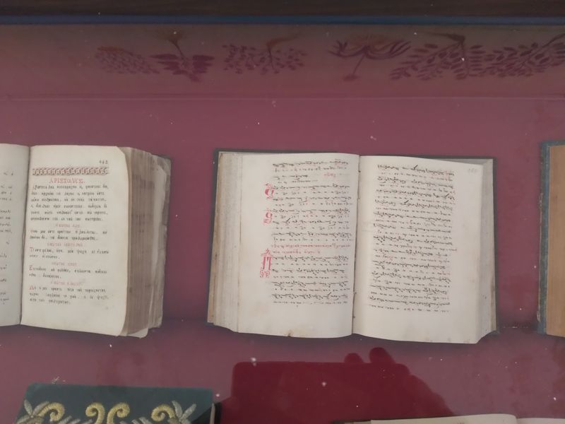 Μαύρα μουσικά σημάδια πάνω από συλλαβές και κόκκινα διακοσμητικά αρχικά στις δύο σελίδες ενός βιβλίου.