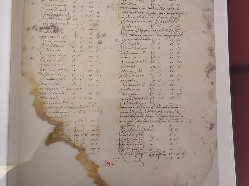 Δύο στήλες ελληνικής γραφής και αριθμητικών ενδείξεων σε κηλιδωμένο φύλλο με φθαρμένη κάτω αριστερή άκρη.
